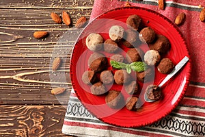 Plate with tasty chocolate truffles on wooden table