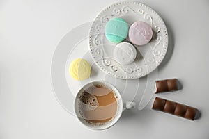 Plate with tasty colorful macarons and cup of coffee on white background