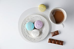 Plate with tasty colorful macarons and cup of coffee on white background