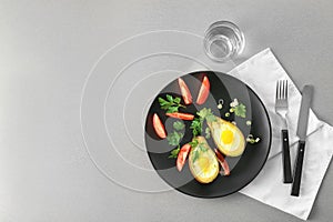 Plate with tasty eggs baked in avocado and fresh tomatoes on table