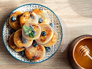 Plate with tasty fluffy pancakes with blueberries, honey