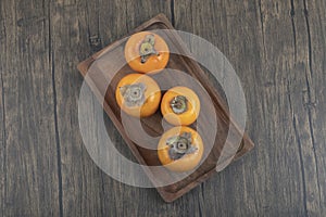 Plate of tasty fuyu persimmon fruits on wooden surface