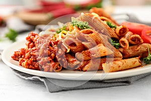 Plate with tasty penne pasta and bolognese sauce on table, closeup