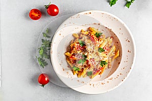 Plate with tasty penne pasta in tomato sauce, chicken meat and vegetables on grey table. italian penne pasta. banner, menu recipe