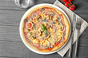 Plate with tasty pizza on wooden table, top view