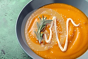 Plate with tasty pumpkin cream soup on color table