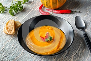 Plate with tasty pumpkin cream soup on light table