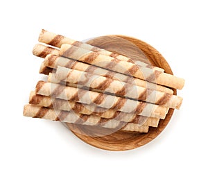 Plate with tasty wafer roll sticks on white background, top view.