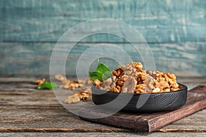 Plate with tasty walnuts on wooden table.