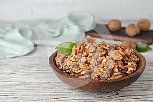 Plate with tasty walnuts on wooden table.