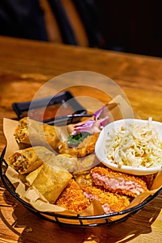 A plate of Thai snacks, fried shrimp cakes, fried spring rolls and vegetable salad