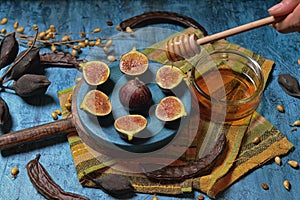 Plate with three cut figs and one whole and container with honey photo