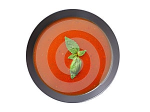 Plate of tomato soup with basil isolated on a white background