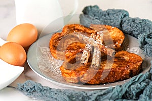 Plate with traditional homemade Torrijas, cinnamon stick,milk and eggs. Typical Lent and Easter dessert in Spain