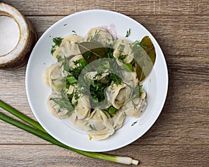 plate of traditional Russian dumplings sprinkled with herbs on wooden table