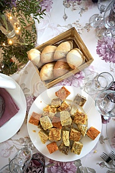 A plate of traditional Spanish omelet squares beside a basket of bread rolls