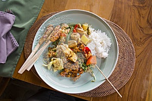 Plate of typical Balinese, Thai, Indonesian food with chicken sa