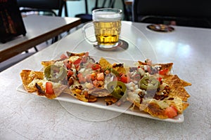 plate of typical Mexican nachos accompanied by a very fresh beer. delicious food for parties and being happy with