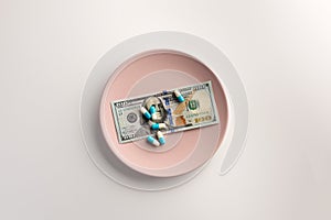 A plate with US dollar bank note and pills isolated on white