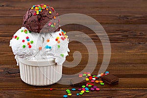 Plate of vanill aand and chocolate ice cream scoop swith sprinkles and waffle cones on wooden background with copy space