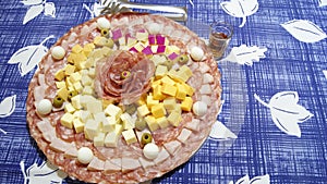 Plate with various types of cheese, salami, quail egg, green olives and glass of liqueur and tagger,