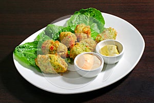 Plate with vegetable cutlets on lettuce and sauce