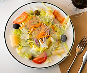 Plate with vegetable salad with cabbage, lettuce, carrots, onions, tomatoes, olives