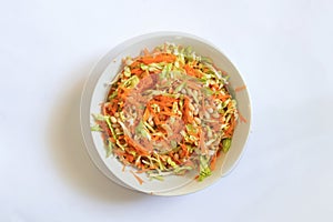 Plate with vegetable salad on a white carrot beans cabbage