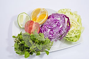 A plate of vegetables and fresh lime and lemon.