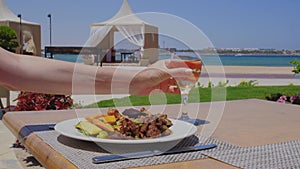 Plate with vegetables and meat. A glass of white wine in a woman's hand.