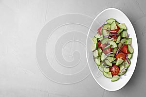 Plate of vegetarian salad with cucumber, tomato and onion on light background. Space for text