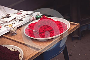 A plate of vermillion red powder with small colourful Indian Traditional Rajasthani Sindhoor Boxes in Guruvayur street,India