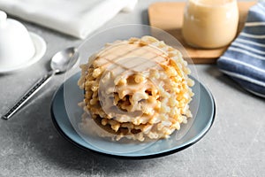 Plate with waffles and condensed milk on grey table