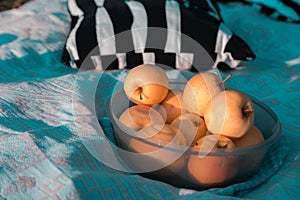 Plate with yellow apples close-up on a blue bedspread on a sunny day on a picnic