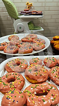 Plate of yummy vanilla cake donuts with pink icing and sprinkles