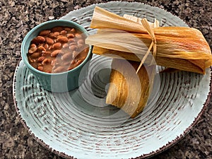 Plated beautiful homemade Tamale with a side of beans