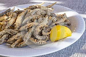 Plateful of Battered and Fried Smelts Served with a Wedge of Lemon Closeup