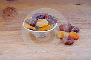 Plateful of Organic dried apricots and Spilled dried apricots on Wooden Background