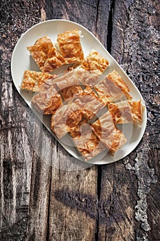 Plateful Of Serbian Traditional Crumpled Cheese Pie Gibanica Set on Old Weathered Cracked Grooved Wooden Garden Table photo