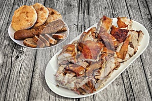 Plateful Of Spit Roasted Pork Slices With Baguette Slices And Leavened Pitta Flatbread Loaves Set On Old Pinewood Picnic Table