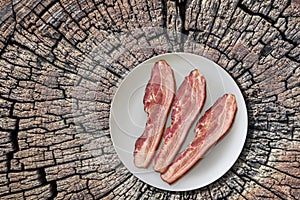 Plateful of Three Pork Belly Bacon Rashers on Old Cracked Stump Surface