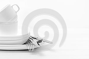 Plates, cups and silver cutlery on light white background