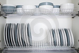 The plates are flat and deep stacked on the dryer in the kitchen