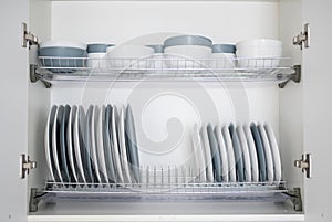 The plates are flat and deep stacked on the dryer in the kitchen