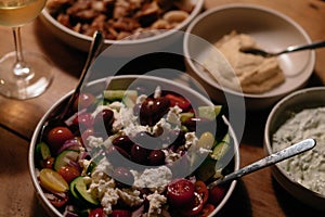 Plates of homemade rustic greek food on a table with greek salad calamari hummus wine and beer