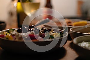 Plates of homemade rustic greek food on a table with greek salad calamari hummus wine and beer