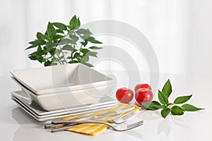 Plates and kitchen utensils on a white table
