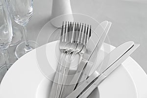 Plates with knives forks on light grey table, closeup