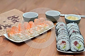 Plates of maki sushi rolls and nigiri sushi with salmon and shrimp japan food on the table with soy sauce