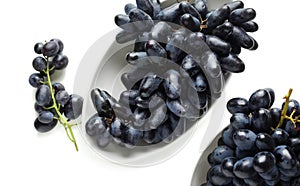 Plates with ripe sweet grapes on white background